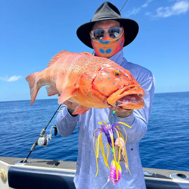 Person holding a large orange fish on a boat with a blue sky background